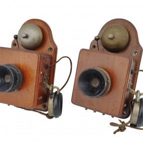 Pair of antique wooden wall telephones with bells and receivers.